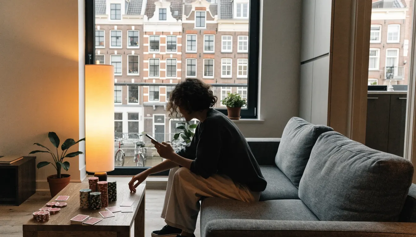 Persoon op bank in Amsterdams appartement met casino fiches en speelkaarten op tafel
